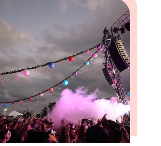 Festival main stage with garlands, balloons, and pink smoke